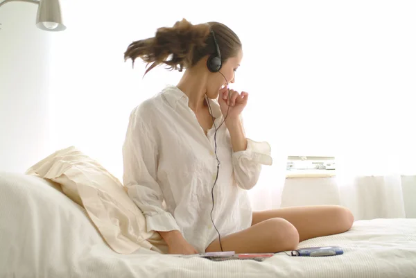 Hermosa chica escuchando música en la cama — Foto de Stock