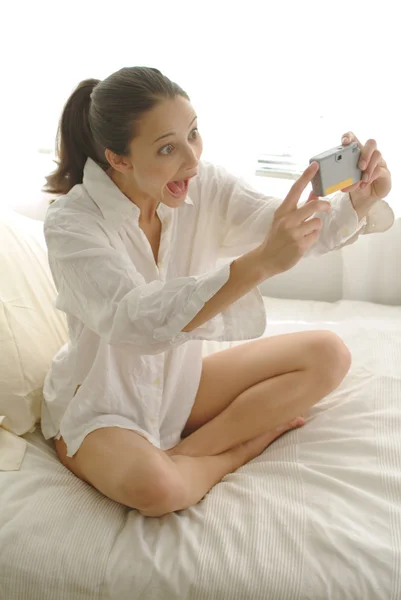 Bruneta žena na posteli s selfy na její fotoaparát Stock Obrázky