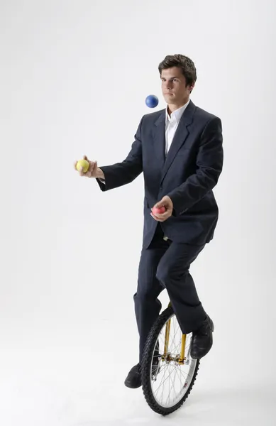 Juggling businessman on unicycle — Stock Photo, Image
