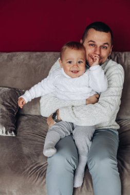 Genç bir baba, küçük çocuğuyla kanepede çok eğlenir.