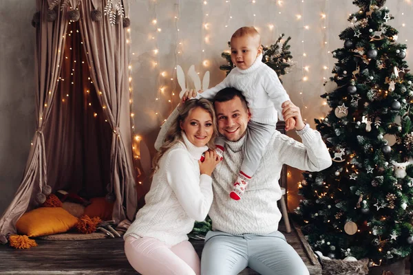 Família feliz com um bebê em decorações xmas. — Fotografia de Stock