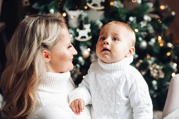 Retrato de la madre se divierte con su bebé al lado del árbol de Navidad —  Fotos de Stock