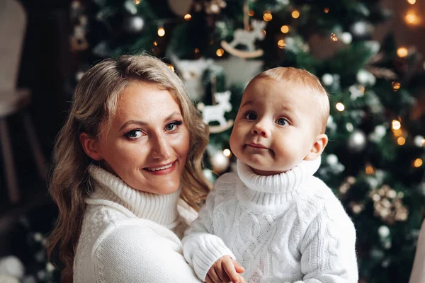 Portret van moeder heeft plezier met haar baby naast de kerstboom en verheugt zich — Stockfoto