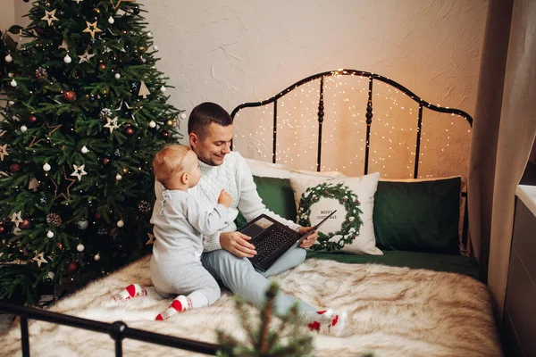 Un hombre fuerte en la ropa de Año Nuevo viendo una serie de televisión en la cama con un niño —  Fotos de Stock