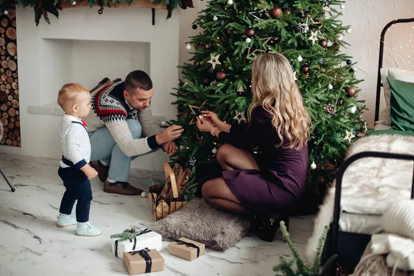 Pequeña familia encantadora poniendo decoraciones en el árbol de Navidad —  Fotos de Stock