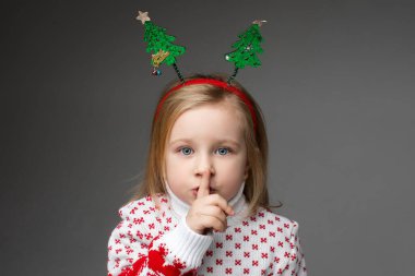 Dudaklarına yakın bir parmakla sessizlik işareti gösteren bir çocuk.