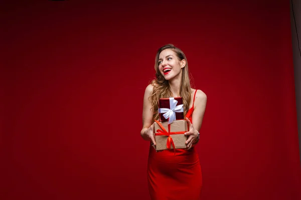 Modelo de moda feminina bonita em vestido vermelho detém um monte de pequenas caixas com presentes — Fotografia de Stock