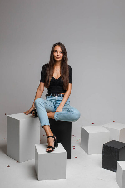 female model in re skirt and denim jeans poses for the camera on black and white cubes