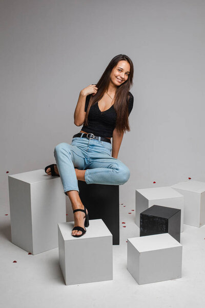female model in re skirt and denim jeans poses for the camera on black and white cubes