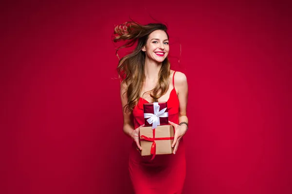 빨간 드레스를 입은 아름다운 여성 패션 모델에는 선물 과 기쁨 이 담긴 작은 상자들이 많이 들어 있다 — 스톡 사진