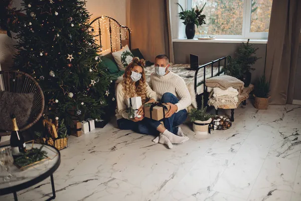 사랑하는 아름다운 부부가 크리스마스 트리 옆 바닥에 앉아 있다 — 스톡 사진