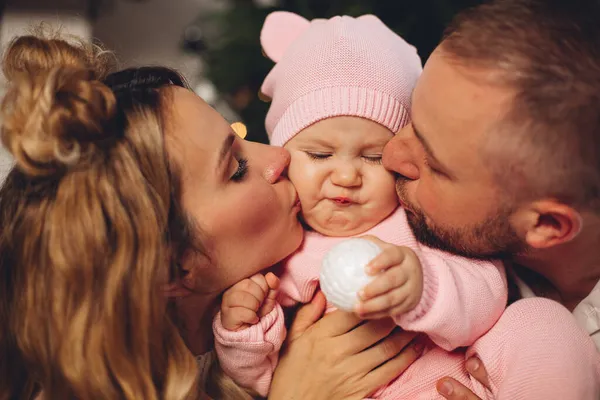 Föräldrar kysser liten flicka i rosa. — Stockfoto