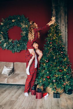 Genç, gülümseyen bir çift Noel arifesinde bir evi dekore ediyor.