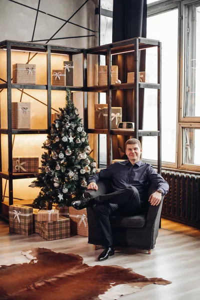 Successful man in arm-chair in Christmas interior. — Stock Photo, Image