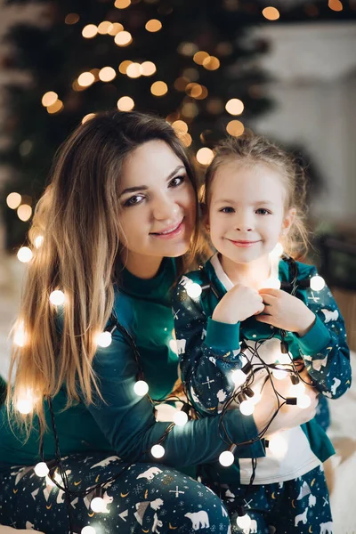 어린 어머니와 귀여운 딸을 돌보며 크리스마스 조명을 즐긴다 — 스톡 사진