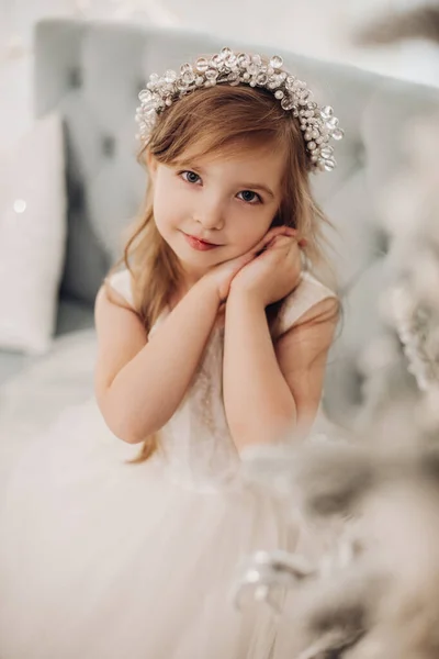 漂亮的小女孩的画像，面带微笑地坐在家里的沙发上 — 图库照片
