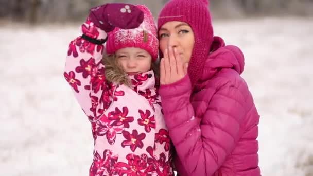 Mutter und Tochter blasen einen Kuss an einem schönen frostigen Wintertag im rosafarbenen Familienoutfit — Stockvideo