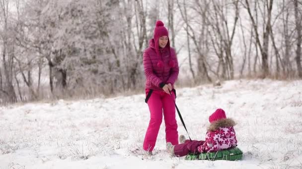 Junge Mutter und kleine Tochter im Schnee. Kopierraum. Familie hat Spaß an sonnigem Wintertag im Freien — Stockvideo