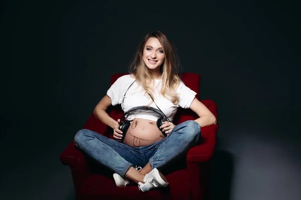 Zâmbind femeie însărcinată cu căști mari pe burtă . — Fotografie, imagine de stoc