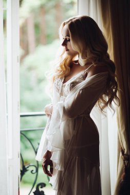 Muhteşem gelin balkon yakınında duran ve büyük pencerede bakıyor.