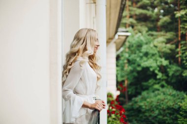 Muhteşem sarışın gelin balkonda yürüyüş ve onu damat bekliyor.