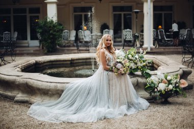 Zarif şehvetli sarışın gelin çiçek tutan ve kamera poz.