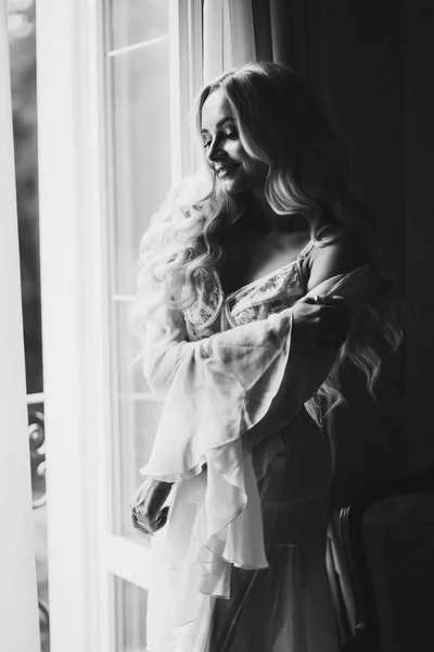 Gorgeous bride standing near balcony and looking in big window. — Stock Photo, Image