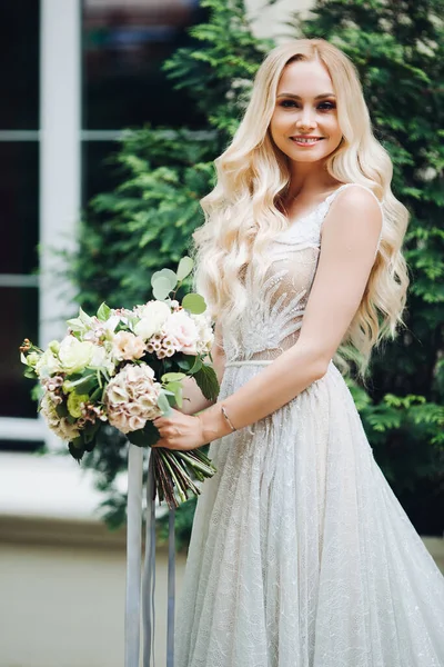 Elegante Blondine Braut lächelnd, hält Hochzeit boquet. — Stockfoto