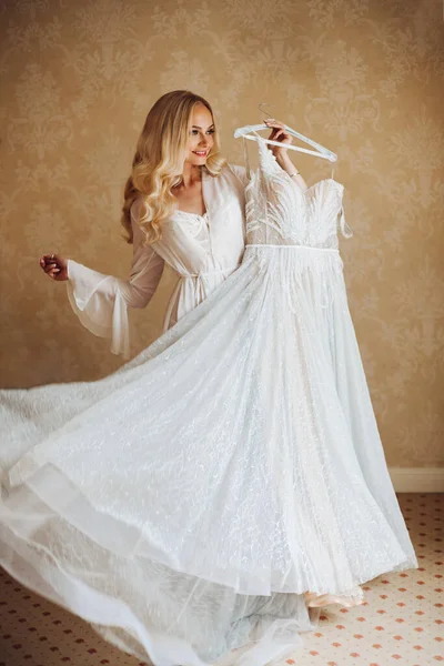 Gorgeous bride standing near balcony and looking in big window. — Stock Photo, Image