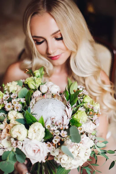 Bonita noiva segurando buquê de casamento e posando com os olhos fechados . — Fotografia de Stock