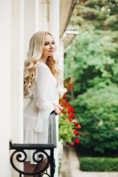 Prachtige Blondie bruid wandelen op het balkon en wachten op haar bruidegom. — Stockfoto