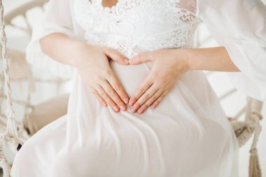 Salıncak çiçeklerle oturan güzel sarışın hamile kadın.