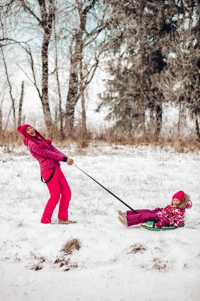 Χαριτωμένη οικογένεια έχουν τη διασκέδαση σε ένα χειμερινό πάρκο. Η μαμά και η κόρη παίζουν το χειμώνα με ζεστά ρούχα, διασκεδάζουν, αγκαλιάζονται, χαίρονται. Ημέρα οικογένειας — Φωτογραφία Αρχείου