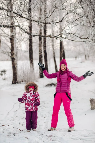 Leuke familie veel plezier in een winterpark. Mam en dochter spelen in de winter in warme kleren, hebben plezier, knuffelen, verheugen zich. Familiedag — Stockfoto