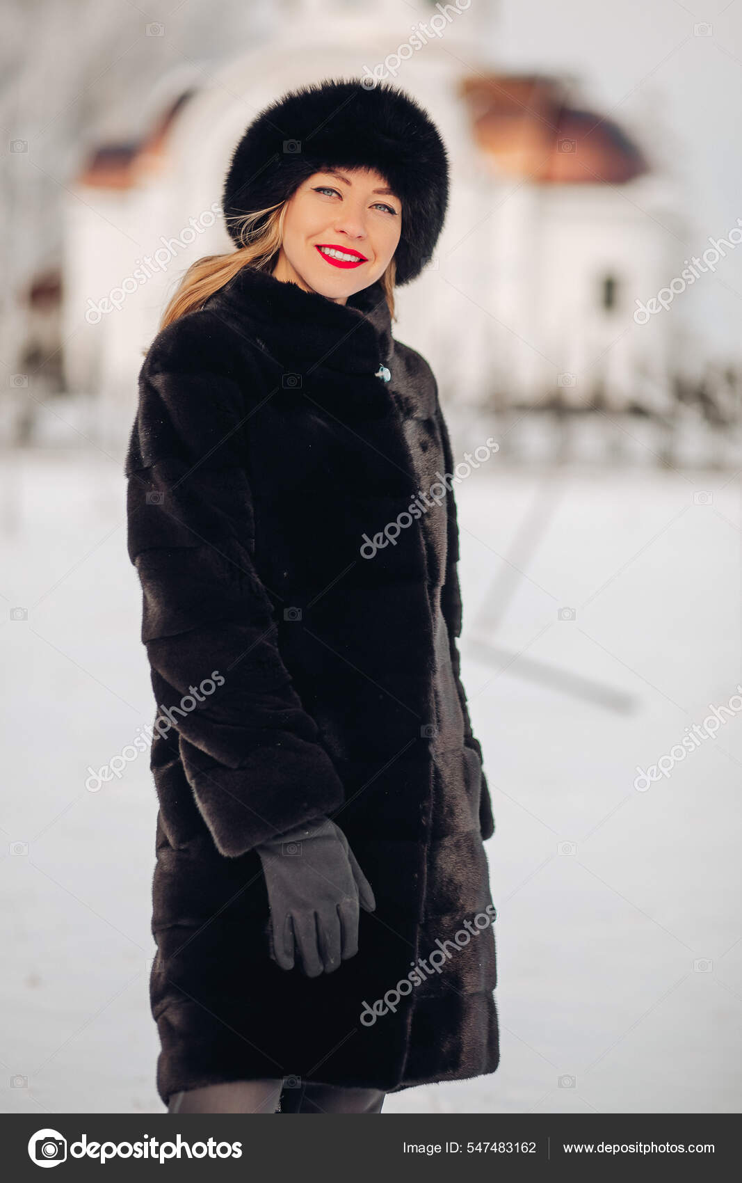 Une belle jeune femme en chapeau de fourrure noire et manteau de fourrure portrait. Une jolie fille russe sourit et regarde dans le cadre levres rouges maquillage lumineux. Photo de stock