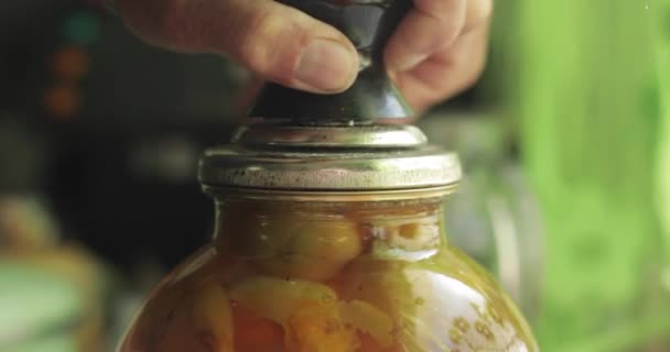 Een man rolt een pot fruitconserven op.. — Stockvideo