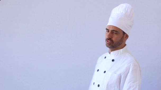 Chef barbudo de mediana edad en toque blanco y uniforme de pie mirando a la cámara con copyspace en blanco — Vídeo de stock