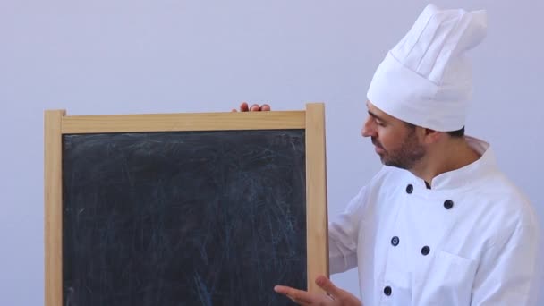 Chef de meia-idade barbudo em toque branco e uniforme de pé olhando para a câmera com copyspace em branco — Vídeo de Stock