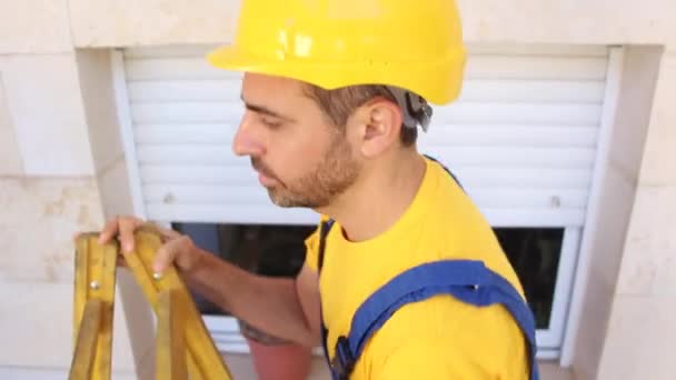 Bouwer met werknemer doeken staan op een ladder — Stockvideo