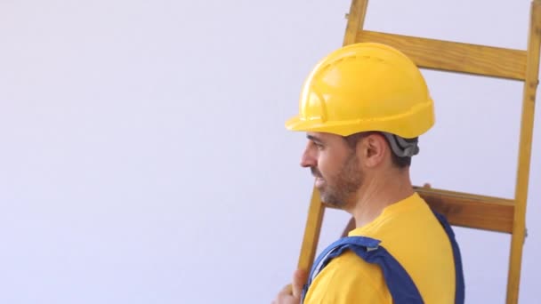 Строитель с рабочими тканями стоит на лестнице — стоковое видео