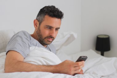 yatakta onun akıllı telefon kullanıyor