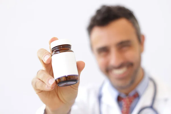 Smiling doctor holding up a bottle of tablets — Stock Photo, Image