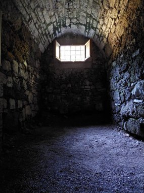 Taş duvarları ve küçük bir kapağı olan karanlık Avrupa ortaçağ zindanı