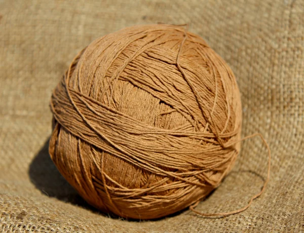 Beige ball of threads on texture of a sacking
