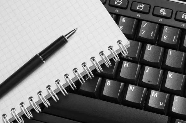 Caderno e caneta no teclado preto . Fotos De Bancos De Imagens