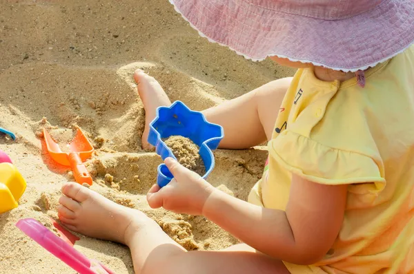 Liten flicka och sand leksaker Stockfoto