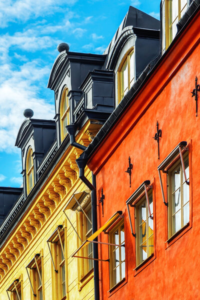 Old red and yellow facade of buildings with windows and blue sky - Stockholm, Sweden