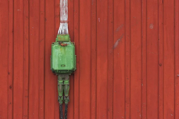 Electrical box on a wooden red background, poweroutlet in green