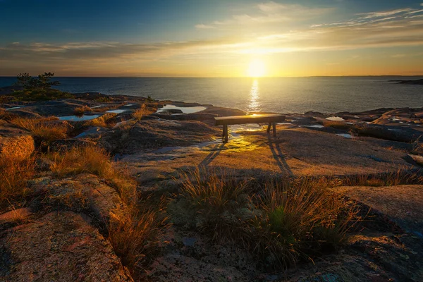 Ανατολή του ηλίου πάνω από ένα παγκάκι σε μία σκανδιναβική ακτή — Φωτογραφία Αρχείου