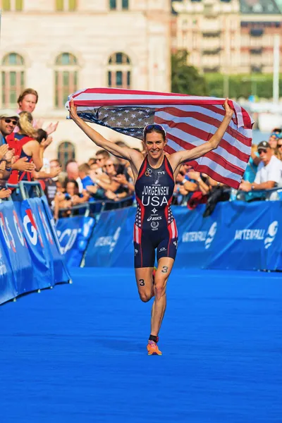 STOCKHOLM - AUG, 24: The winner Gwen Jorgensen running to the finish line with the USA flag in the Womens ITU World Triathlon Series event Aug 24, 2013 in Stockholm, Sweden — Stock Photo, Image